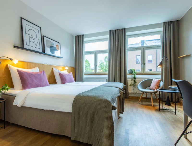 Hotel room with bed and two windows. Photo.